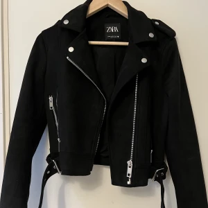 Bikerjacka i mocka - Zara - Säljer denna bikerjackan i mocka köpt från zara. Jackan är knappt använd och är som gott som ny. Den har tre fickor framtill varav två är riktiga. Den har snygga deltaljer i silver och är i strl Xs, men skulle nog säga att den även passar strl S. 