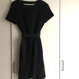 Svart figursydd klänning  - Super framhävande och snygg klänning. Den är figursydd och har en slits baktill som är cirka 10 cm. Inga defekter och använd ca 3 gånger.