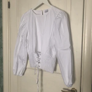Fin blus - Vit blus med resår nertill i midjan med snörning framtill. Festlig och somrig Använd fåtal gånger men är i mycket gott skick.
