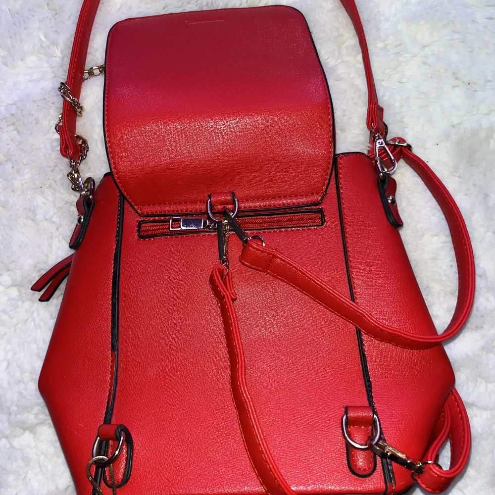 En röd väska som kan även användas som ryggsäck.. Väskor.