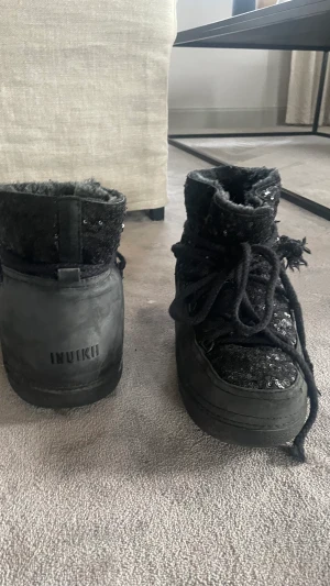 Inukii - Svarta inukii med paljetter på, dom är i storlek 41 men små i storleken. Själv har jag 39 och kan ha dom, skulle hälst vilja byta mot andra inukiis eller uggs ( eller några andra vinter skor) men kan även sälja för 1000kr + frakt 
