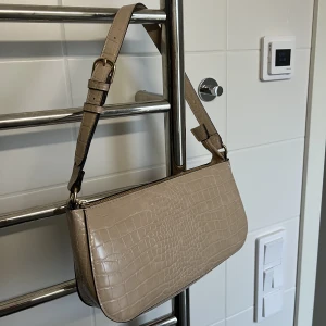 Väska  - En axelväska i en beige färg. Konstskinn med strukturer. 