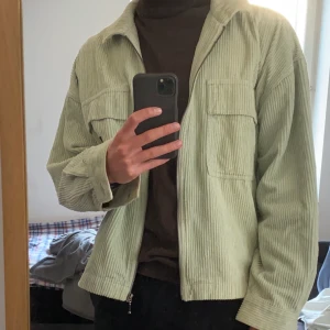 Grön Jacka i Manchester tyg  - En skitsnygg grön jacka i Manchester material från Junkyard. Jackan är i perfekt skick och har en skön mintgrön färg. Jackan är lite oversized och passar allt från S-L beroende på hur man vill att den ska sitta.