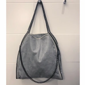 Väska  - Hej! Säljer nu min väska som ska likna stella McCartney väskorna. Väskan är i en grå färg som skiftar lite åt det glittriga hållet i vissa ljus. Väskan har en dragkedja och 3 innerfack . Storlek, 35 cm i bredd och 40 i höjd.🥰