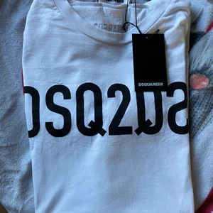 Dsquared2 tshirt - En snygg vit T-shirt från Dsquared2. Oanvänd med lappen kvar. Kvitto från NK finns. Nypris 2099kr, säljer för 1500. Storlek XL och är sann till storleken. Köparen står för frakt därför förhandlingsbart pris😄