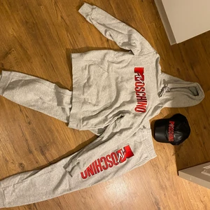 Moschinoset  - Grå Moschinoset som inte längre går att köpa i butik. Tillverkades i samarbete med H&M. Knappt använt så i mkt gott skick. Hoodie, byxor och keps. Säljes endast som set. Kommer inte att pruta på priset. 