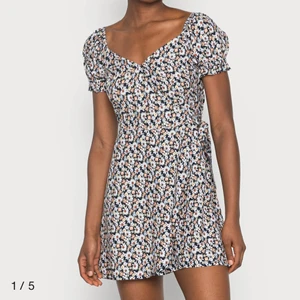 Blommig sommarklänning  - Säljer denna söta sommarklänningen som de första bilderna visar, men i en mörkblå färg (3e bilden) med ljusblåa blommor💙🥰 Den är en omlottmodell med knytning i sidan, och därför lika perfekt att ex slänga över en bikini, som att ha en vanlig sommardag🌸