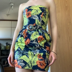 Blommig klänning - Fin axelbandslös klänning! Passar perfekt till nu till sommaren enligt mig. Väldigt vackert mönster, medföljande skärp samt 🙏FICKOR🙏 vilket är ett stort plus enligt mig