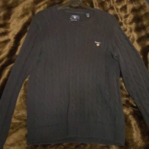 GANT kabelstickad rundhalsad tröja - En elegant kabelstickad GANT tröja som har några år på nacken men den är fortfarande i bra skick och passar bra med bara en t-shirt under eller med en skjorta.