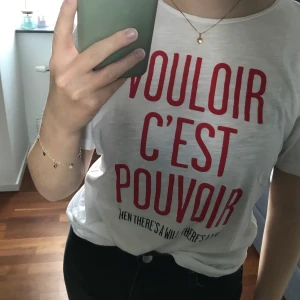 T-shirt  - Vit t-shirt med tryck från KappAhl i storlek S. Är lite defekt, se bild 2 och 3. Den har en gul fläck längst ner på kanten, vilket inte syns när man stoppar in tröjan. Den har även ett litet hål på ryggen. 