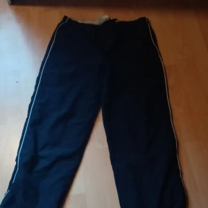 Foder byxor - Svarta byxor med vita remmor på sidorna i storlek M. Använda 1-3 gånger. Dom är inte så stretchiga. Dom har dragkedja fickor och har även dragkedjor längs ner på byxorna. Säljer dom då de inte passar längre.