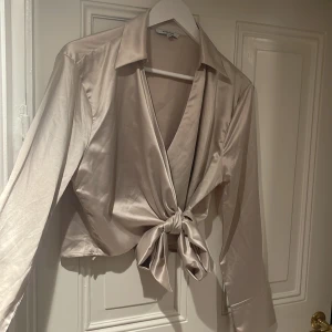 Blus från Chiquelle  - Ljusbeige blus från Chiquelle som man knyter där fram, storlek M. 80kr+frakt