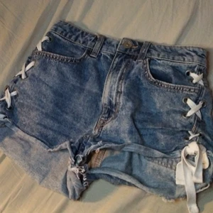 Jeans shorts med snören på sidan. - Snygga jeansshorts med snörning om sidan. Säljer då de är för små. Bor i jakobsberg men kan mötas vid allt som nås av SL.