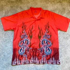 Kortärmad skjorta med motiv - Röd kortärmad skjorta med skitcoolt motiv på! Endast använd några få gånger, köpt på second hand och har en fläck som borde gå bort i tvätten (har inte tvättat sedan inköp). Kan prova att få bort den :) Annars i bra skick!