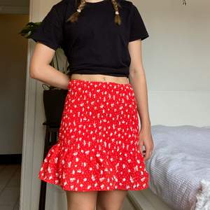 Röd ribbad tight kjol med vita blommor från H&M divided. Aldrig använd. Tvättas i 30°C. ✨