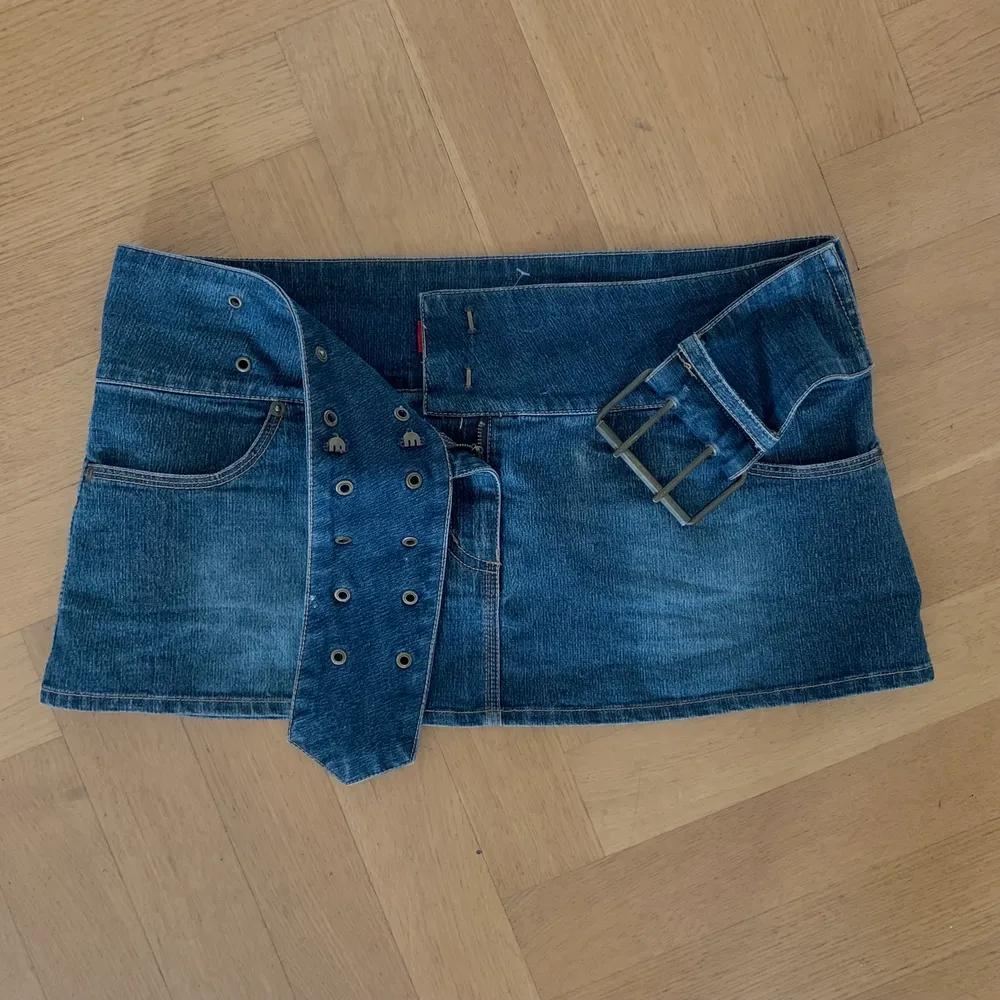 Väldigt kort jeans kjol med ett inbyggt bälte.⭐️ Midjemåttet är 86cm, men om ni mäter på er själva tänk på att inte mäta i midjan utan över höfterna, eftersom den är tänkt att sitta lowrise ⭐️ den kan även justeras lite i storlek då den har ett skärp💗. Kjolar.