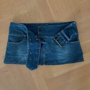 Väldigt kort jeans kjol med ett inbyggt bälte.⭐️ Midjemåttet är 86cm, men om ni mäter på er själva tänk på att inte mäta i midjan utan över höfterna, eftersom den är tänkt att sitta lowrise ⭐️ den kan även justeras lite i storlek då den har ett skärp💗