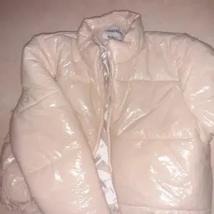 Ljusbeige glansig pufferjacket med lappen kvar. Storlek M från Chiquelle Bilden visar färgen bra, aldrig använd.