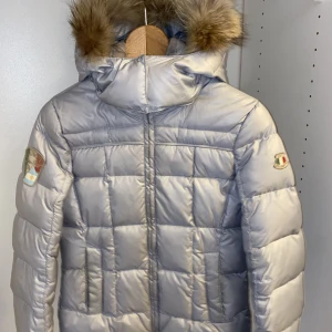 Dolomite vinterjacka/ skidjacka - Använt två säsonger av skidåkning men sparsamt använd i övrigt. Se bilder för de defekter som små fläckar och sminkfläckar på kragen (skickar gärna bilder i chatt) . Den går att tvätta i 30 grader där det bör försvinna.  Luvan går att ta bort. Grå/blå 