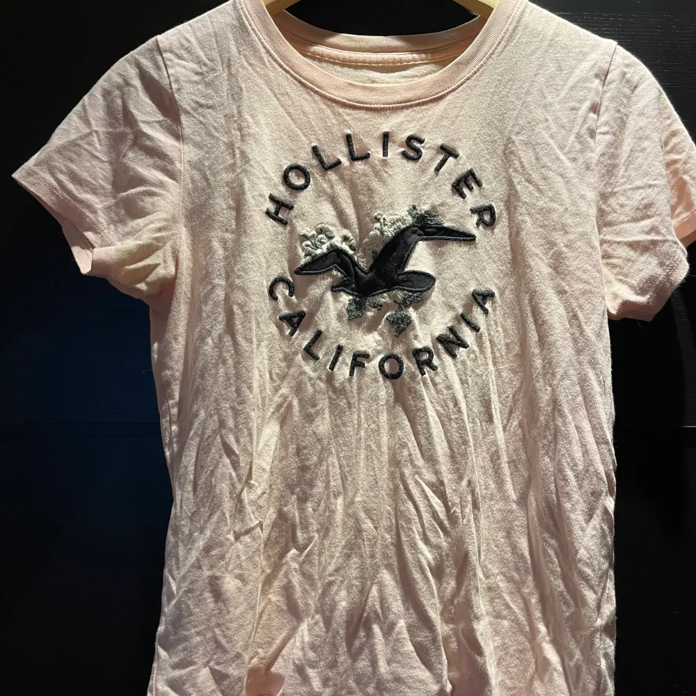 Söt ljusrosa T-shirt med motiv från Hollister. Köpt för några år sedan men bra skick👍. Väldigt mjukt material.. T-shirts.
