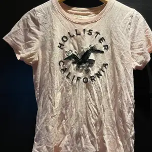 Söt ljusrosa T-shirt med motiv från Hollister. Köpt för några år sedan men bra skick👍. Väldigt mjukt material.