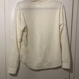 Polotröja vit  - Vit polotröja i sammet. Inköpt i Oslo. Ger skimmer i vissa ljus. Bekväm på, normal passform. Knappt använd