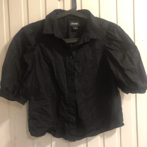 MONKL skjorta  - Svart lite kortare skjorta med puffiga armar.