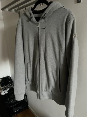 Moose Knuckles Zip Tröja L - Säljer en Moose Knuckles tröja i storlek L. Köptes på Johnells för 3 månader sedan för ca 3900;-.  Har inte kommit till användning, då den är för liten.  Ny pris ca 3900;-  Säljes för 1500;-