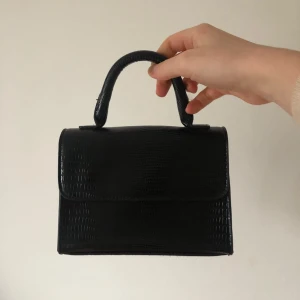 Svart väska - Väldigt söt svart väska, så snygg o användbar. Medföljer axelband men går även bra att fästa en egen kedja eller likande om man vill. Den är i nyskick💕