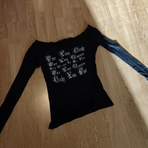 Tröja  - En svart axel tröja med text på. Fick det av min syster sen dess har jag aldrig använt det. 