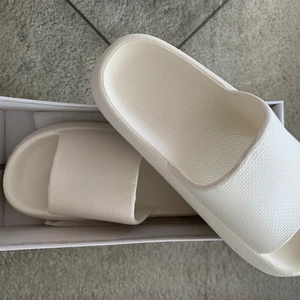 Vita tofflor strl 39-40 - Säljer dessa vita fräscha tofflor i gummi som tyvärr var för små för mig. På kartongen står det strl 41 men de är 39-40 (mer av en 39). Normal passform, dock lite smala i foten. Kritvita i färgen. Aldrig använda. Perfekt till sommaren med sol och bad🤍🤍🤍