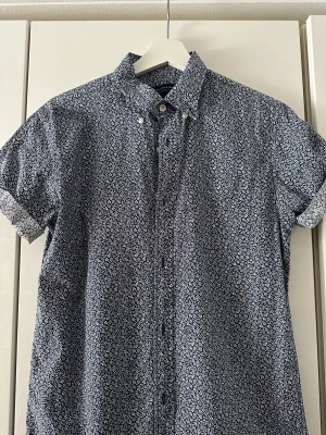 Kortärmad skjorta från Jack n Jones - Blommig blå skjorta från Jack n Jones i bra skick, stl. Small