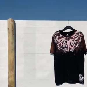 Hand-painted calligraffiti T shirt - The shirt itself is brand new with the tag on, the paint is fabric paint which is whashable at 40 degrees. The size of the T shirt is large, but it’s more like an oversized M.