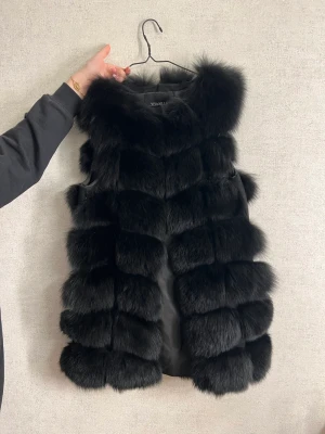 Svart fluffväst - En väst med pels på, bra päls med bra material. Använd 2 gånger.