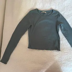 En mörkgrön långärmad tröja från Pull&Bear som inte kommer till användning. Den är använd 1 gång och i superfint skick. Den är lite randig i tyget och har lite volangaktiga sömmar vid ärmarna och nertill. 