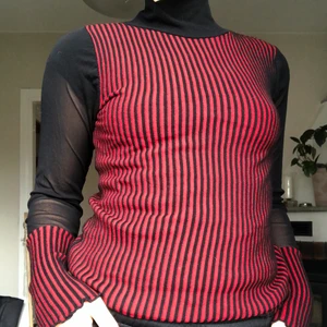 Svart röd polo topp - Jättesmuckrabde passform. Svarta mesh-sektioner och röd-svarta ”resår” områden som gör att passformen blir superbekväm.