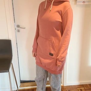 Rosa hoodieklänning - Super fin och jättemjuk knälång hoodie(klänning). Sparsamt använd, nästan nyskick. Varm och gosig insida, perfekt för kommande säsong. Strl 40/42