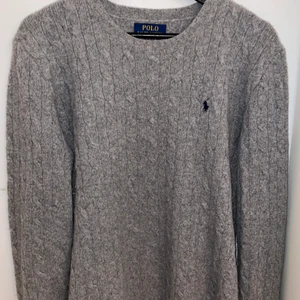 Polo Ralph Lauren - Säljer en fin kabelstickad grå tröja från polo Ralph lauren. Tröjan är i 100% ull. Strl ärXL/TG (18-20). Skulle säga yt det motsvarar strl M. Har använts 2 gånger. Köpt för 1200