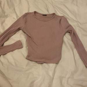 En långärmad ribbad tröja från Gina i storlek xxs men en knytdetalj i ryggen. Lite rosa lila i färgen. Frakt ingår 