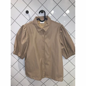 Kortärmad blus i läderimitation  - Kortärmad blus i läderimitation från Vila. Använts 3 gånger. Nyskick. Storlek 38. 100% nylon. 