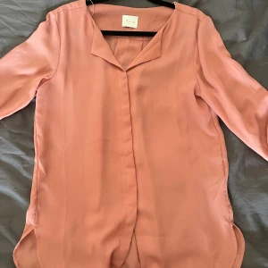 Rosa blus - Jag säljer denna knappt använda blusen från Vila, otroligt fint skick. Den är rosa/beige i färgen och materialet är likt en blus.