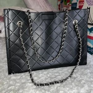 Svart väska - Snygg svart väska från GinaTricot! Aldrig använd så helt ny. 26 cm hög, 35 cm lång o 13 cm bred. 