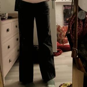 Svarta kostymbyxor - Svarta kostymbyxor, lågmidjade med vida ben. Lite slitna och uppsydda vid höften men snygga.