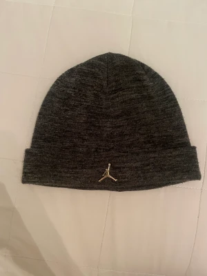 Jordan mössa - Hej jag säljer en grå Jordan mössa med guld logga🤩mössan har inga tecken på användning😁köptes för 400💛bara att fråga efter fler bilder‼️