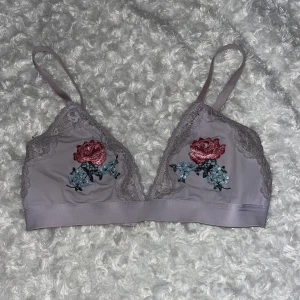 Lila BH - Tunn lila tyg-BH med blommor från HM. Ingen vaddering. Knappt använd, fint skick.