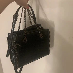 Unik cool väska  - Säljer min unika väska i svart då den inte kommer till användning. Använd ute en gång. Inga skador eller så. Man får med ett långt band sen har den de kortare kedjan. Bandet går att reglera. Cool och rymlig.👍🏼