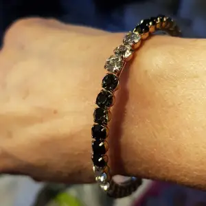 Guldfärgad armband med svarta och vita stenar.