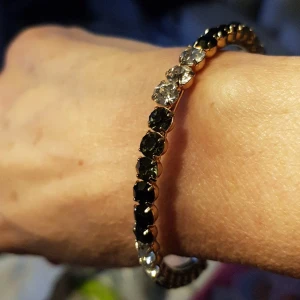 Armband med stenar. - Guldfärgad armband med svarta och vita stenar.