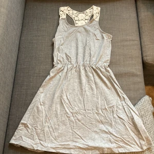 Klänning  - En grå klänning med vita blommor som axelband