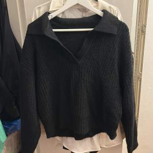 En svart stickad tröja med krage ifrån ginatricot, i bra skick, använd 2 gånger. Storlek L men kort i längden